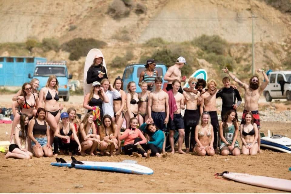 The whole Surf One Camp crew posing on the beach with surfboards