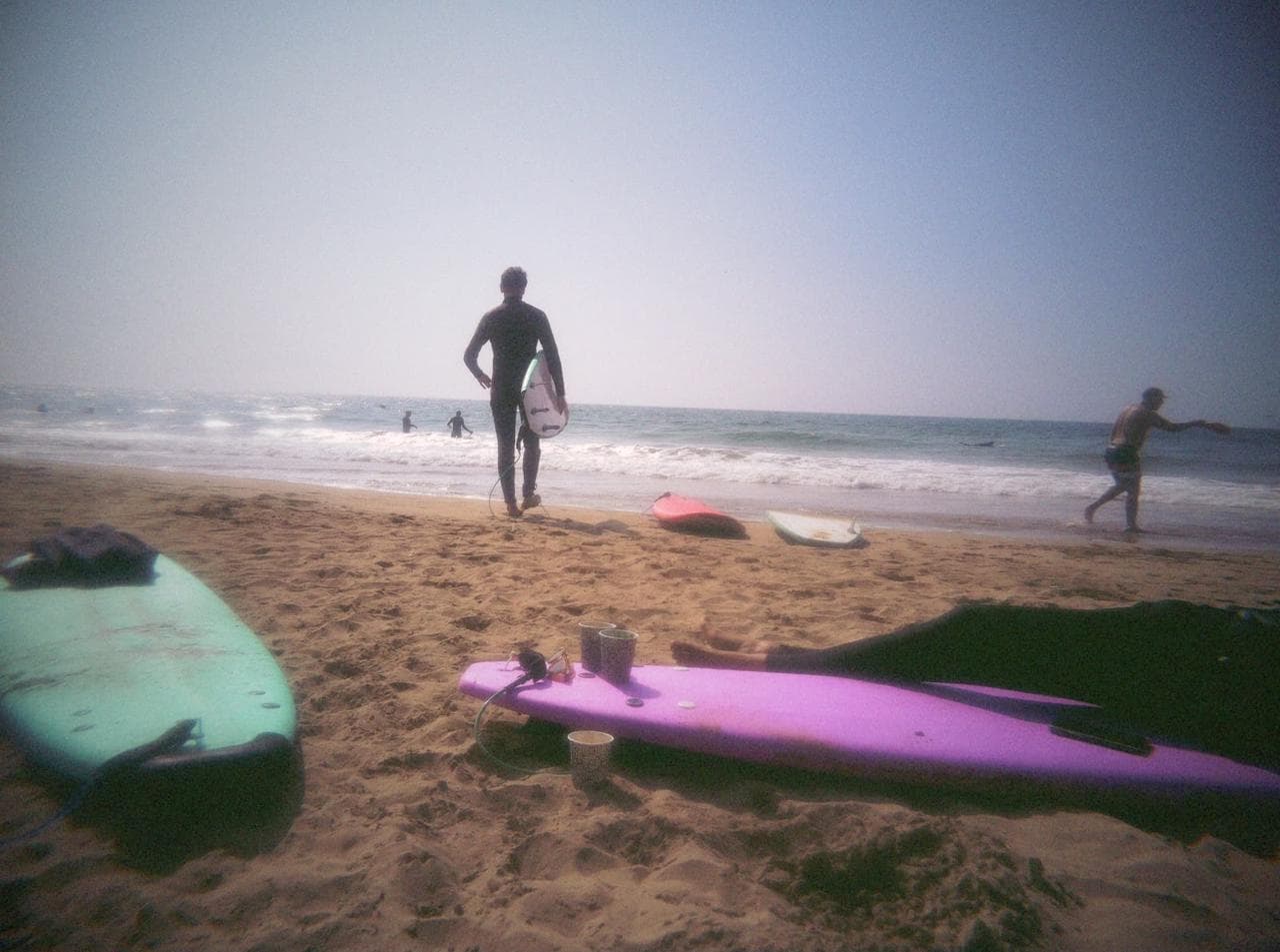 Surfer heading into the waves with soft-top boards on the sand — SurfOne week