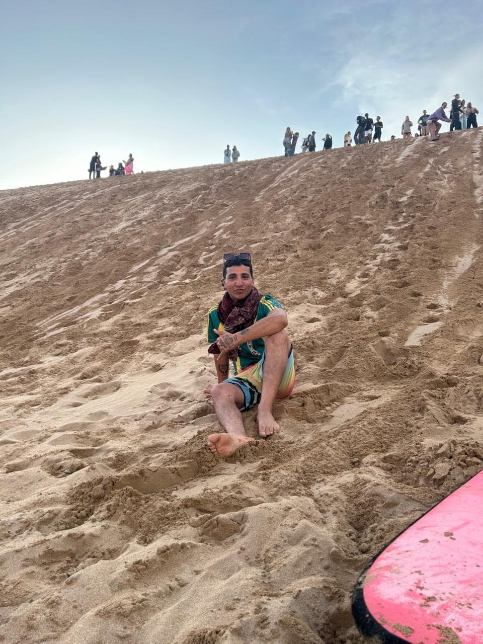 The camp crew sandboarding on the coastal dunes with their guide