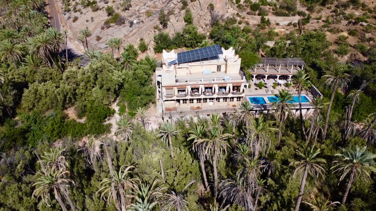 Aerial view of a building surrounded by dense palm valley and mountains